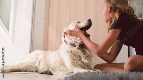 Young teenager girl playing happily with pet dog on the floor