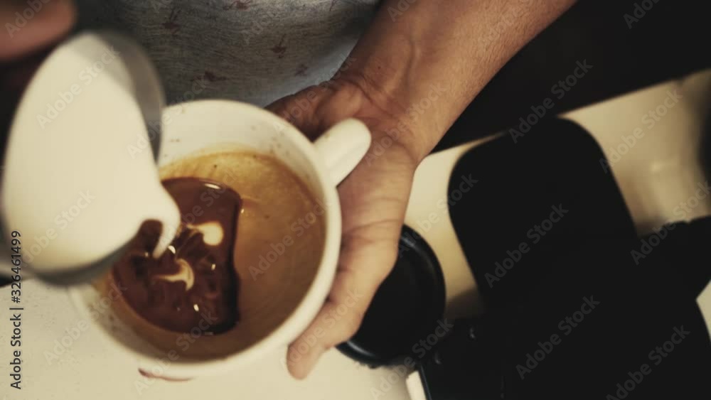 barista holding a cup to pour milk and make a latte art barista holding a cup to pour milk and make a latte art