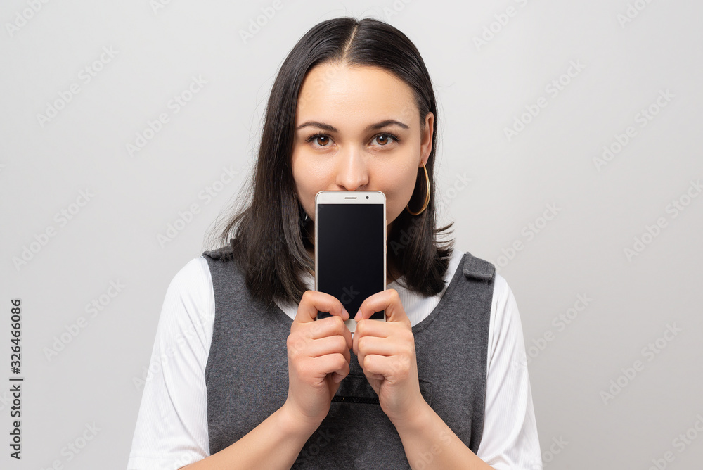 Portrait of a smiling woman showing blank smartphone screen isolated on white Portrait of a smiling woman showing blank smartphone screen isolated on white