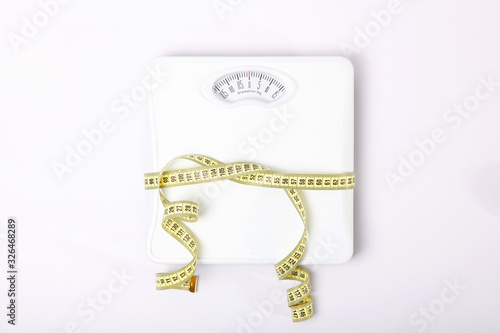floor scales and tape measure on a colored background top view. Healthy lifestyle concept, healthy eating. Body weight control.