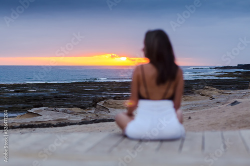 Girl sitting on the beach enjoying the sunset