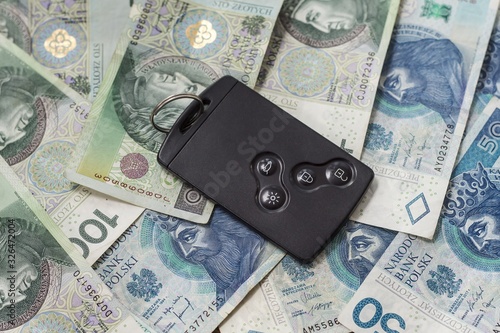 Obraz na płótnie Karta do samochodu leży na banknotach PLN o nominałach 50 i 100 zł w salonie
