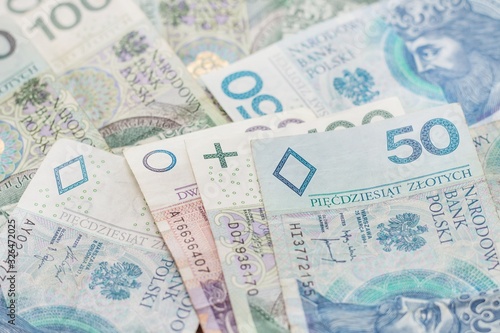 Banknoty PLN o nominałach 20, 50 i 100 zł leżą na stole.