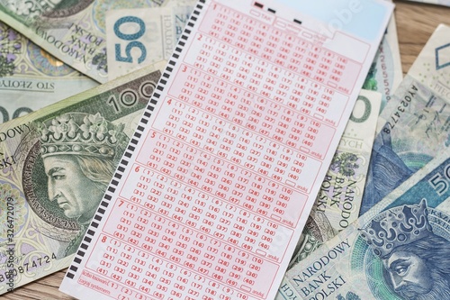 Kupon lotto leży na banknotach PLN.