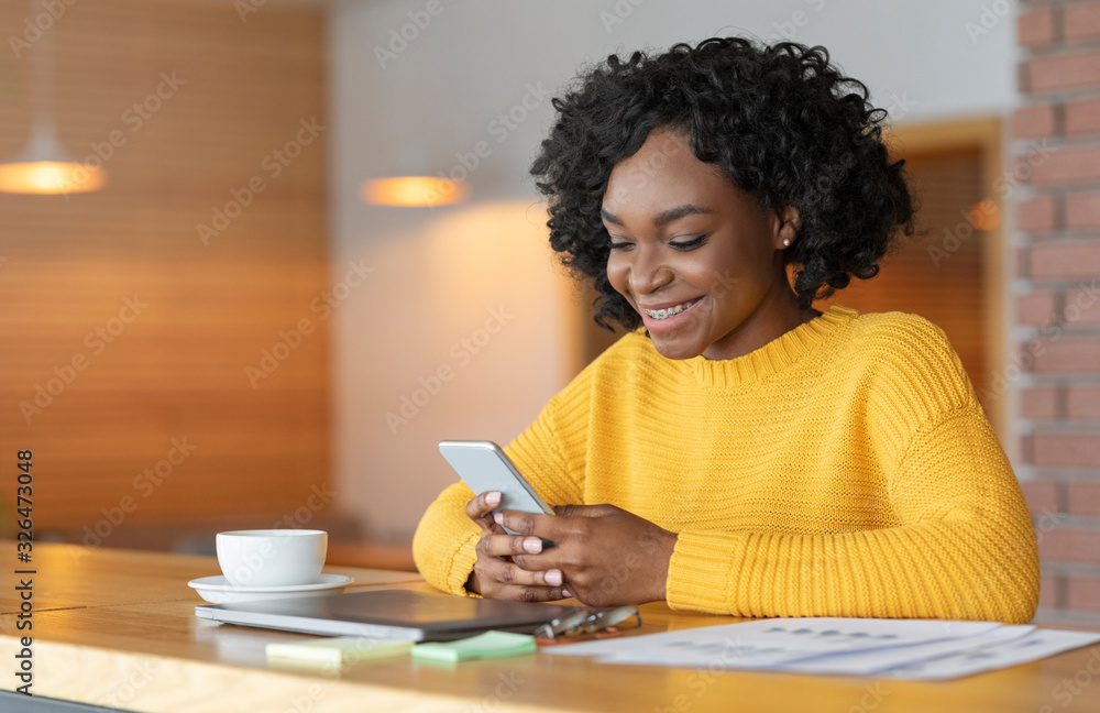 Cheerful afro girl chatting at cafe, using smartphone Cheerful afro girl chatting at cafe, using smartphone