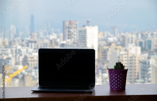 Laptop and cactus plant in a pot at table or office desk on the 21st floor with a beautiful view of city. Photo taken in Beirut, Lebanon © Susie Hedberg