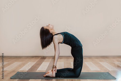 Flexible athletic girl stretching in the gym. a young attractive slender girl is engaged in yoga. arching your back, bridge exercise