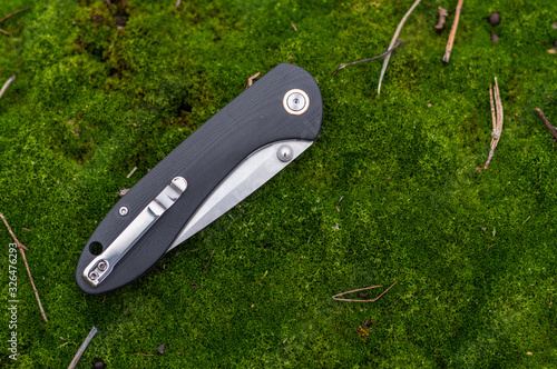 Pocket knife in the folded position. Knife on the moss. photo