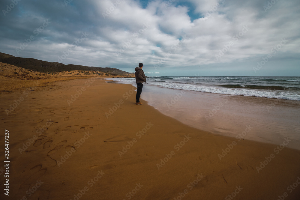 Hombre contemplando las olas del mar en la orilla de la playa Hombre contemplando las olas del mar en la orilla de la playa