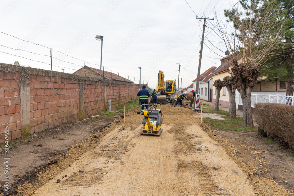 Workers with machinery preparing the road for new asphalt Workers with machinery preparing the road for new asphalt