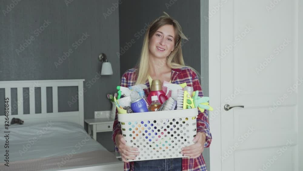 Woman with Basket full of sponges and household chemicals look at camera Woman with Basket full of sponges and household chemicals look at camera