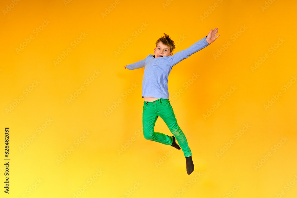 Joyful and happy boy expresses his emotions in a jump, a child is jumping on a yellow background.