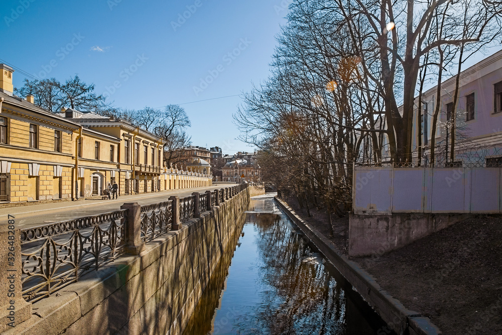 Naklejka premium Shores of the Admiralty Canal with remnants of ice on a bright sunny spring day in March with sunny bunny and blurred background