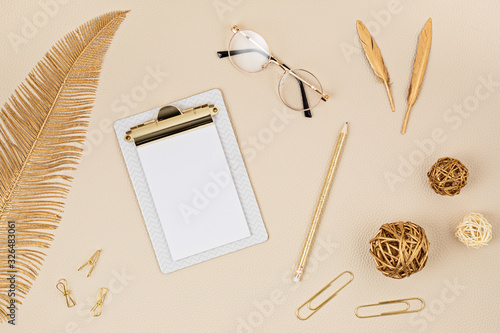 Top view over desktop with notepad, glasses and golden accessories. Home office, business woman, stylish workinf space concept. Flat lay photo