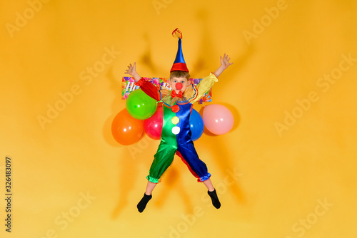 Baby clown jumping on the background of a festive text. The concept of a children's holiday.