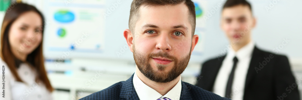 Obraz premium Focus on smart male working in big modern building and discussing important business strategy with younger colleagues and employees. Company meeting concept. Blurred background
