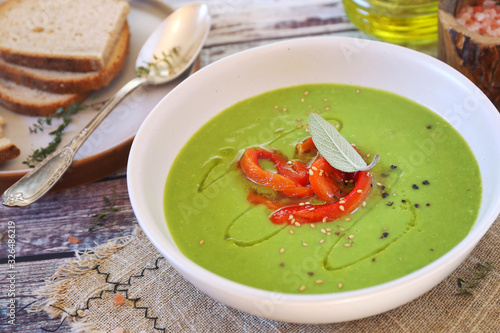 Slika na platnu Green pea soup with spinach, olive oil, red grilled bell pepper dressing