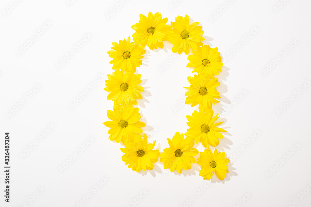 top view of yellow daisies arranged in letter O on white background
