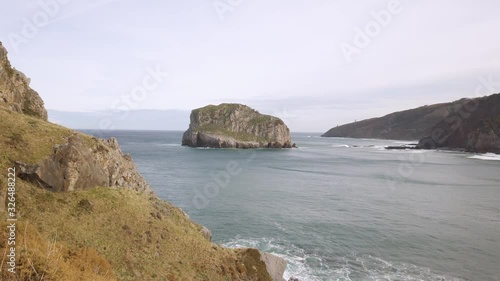 General shot of a coastal island with huge cliffs and green vegetation.