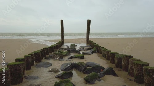 Scenic shot of wavebreakers at low tide on a cloudy day, Zouteland, Netherlands photo