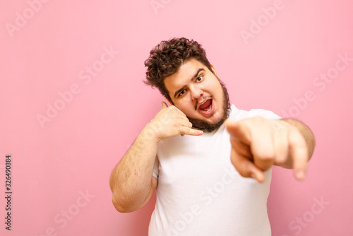 Fotografía Cheerful young overweight man points his finger at the camera and gestures the phone