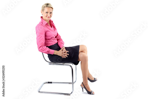 Successful businesswoman sitting sideways on a chair, isolated on white background © Brunbjorn