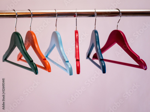 row of colored hangers sway on metal shiny clothes rail isolated on white background