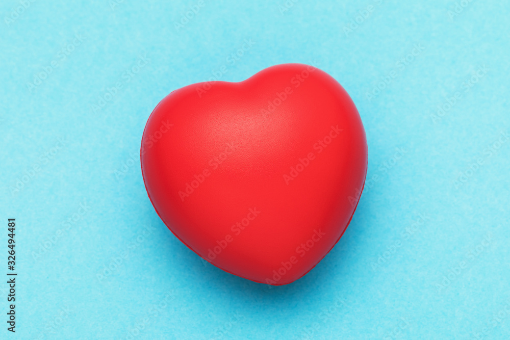 Red toy heart on a blue background, top view