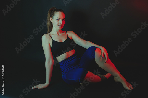 Girl in sportswear doing gymnastics. .Studio, black background. stylized photo with the addition of filters © M.V.schiuma