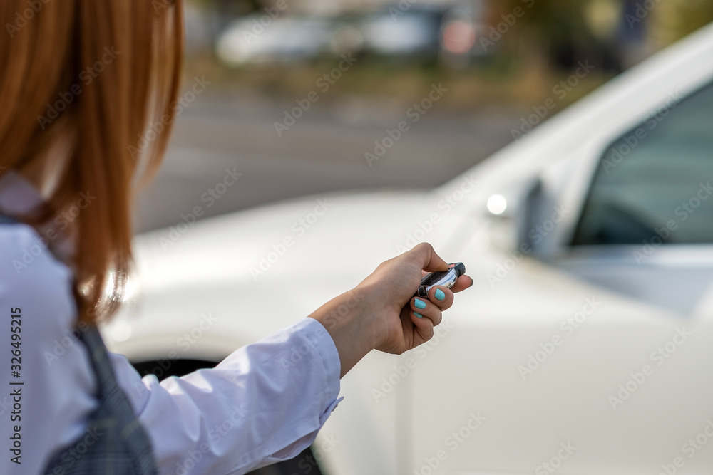 Redhead girl unlocking a car with wireless key. Redhead girl unlocking a car with wireless key.