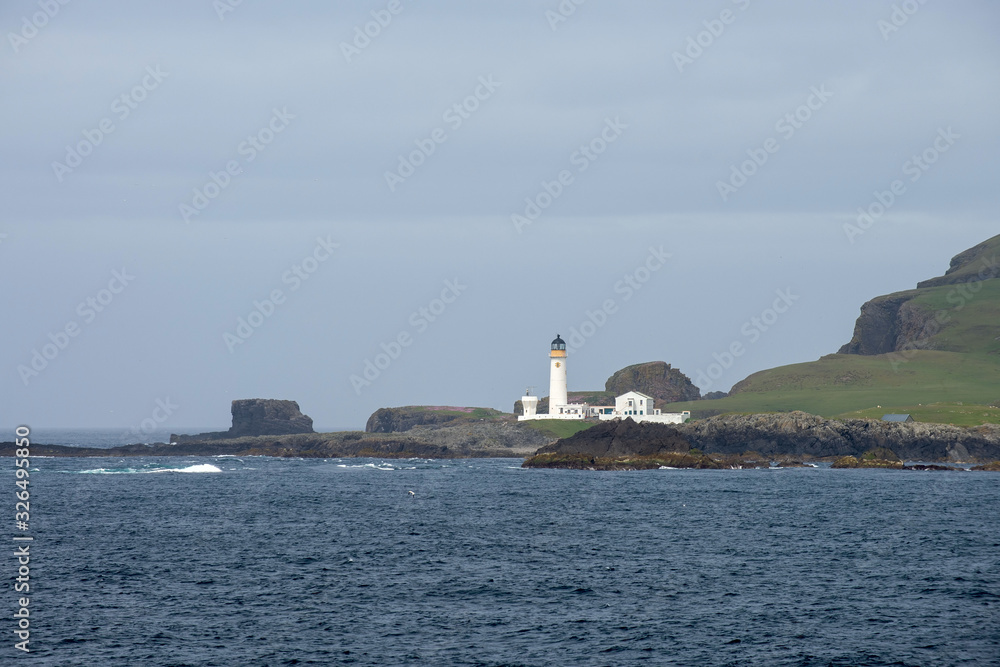 Lighthouse on small island at sea in Scotland, United Kingdom.
