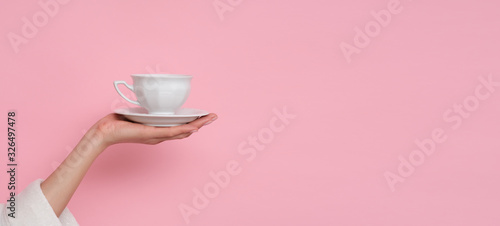 Coffe please. Female hand holding a cup of coffee isolated on pink background. Time to charge battery.