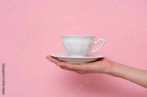 Coffe please. Female hand holding a cup of coffee isolated on pink background. Time to charge battery.