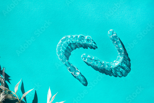 Invisible aligners teeth brackets on blue background with flower shadow