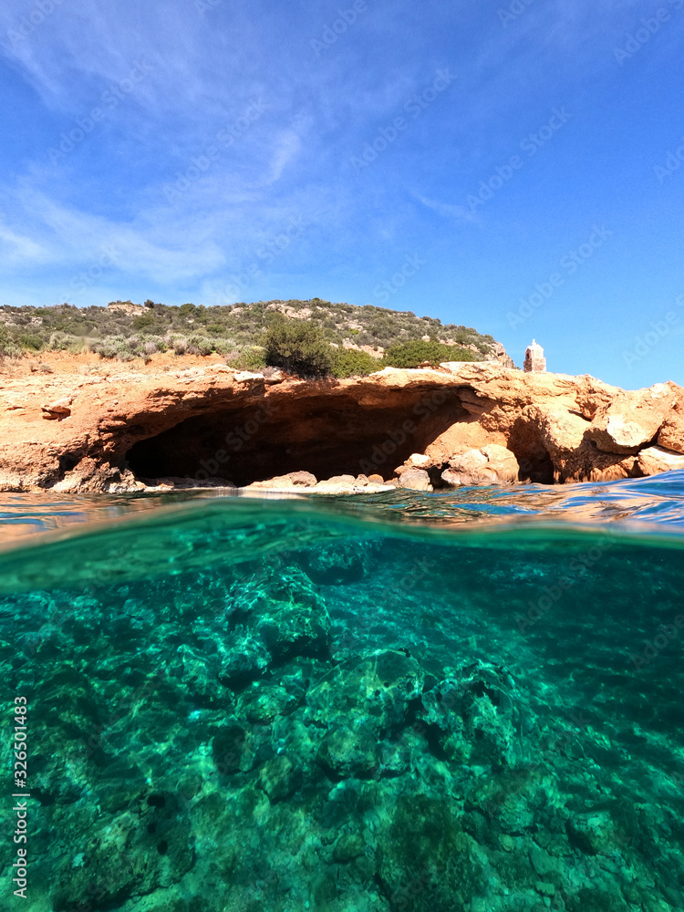 Beautiful underwater split above and below photo of rocky seascape with deep blue sky in tropical exotic island destination