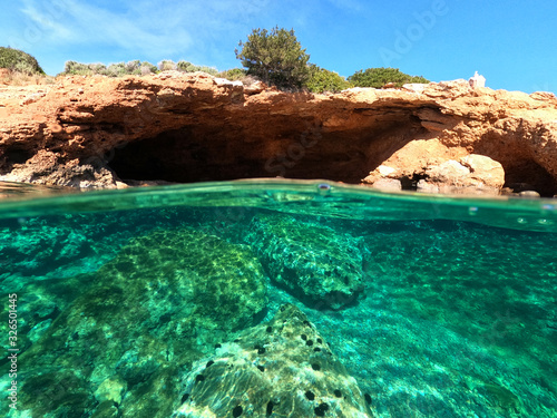 Beautiful underwater split above and below photo of rocky seascape with deep blue sky in tropical exotic island destination