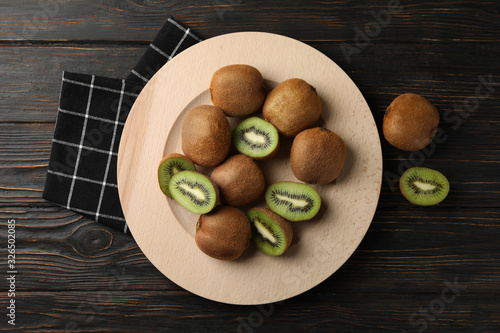 Plate with ripe kiwi on wooden table  top view