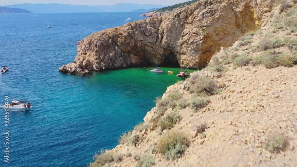 Tourists reaching through yachts and relaxing on the less crowded Golden bay beach beside huge big rocks, Krk island, Croatia. Aerial. Tourists reaching through yachts and relaxing on the less crowded Golden bay beach beside huge big rocks, Krk island, Croatia. Aerial.