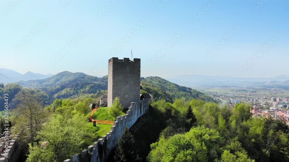 Aerial of the ancient tower of old castle of Celje on top of the hill with view of the urban city around. Forward moving drone. Aerial of the ancient tower of old castle of Celje on top of the hill with view of the urban city around. Forward moving drone.