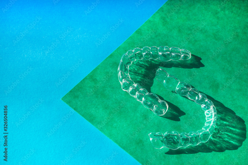 Invisible aligners teeth brackets on blue background Invisible aligners teeth brackets on blue background