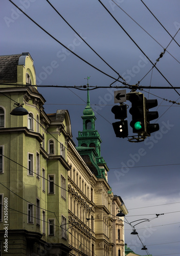 Vienna street with buildings and green tower with a green traffic light and an arrow to the left.