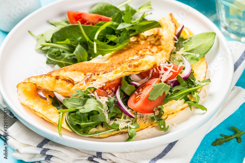Photography Omelette with green leaves at white plate.