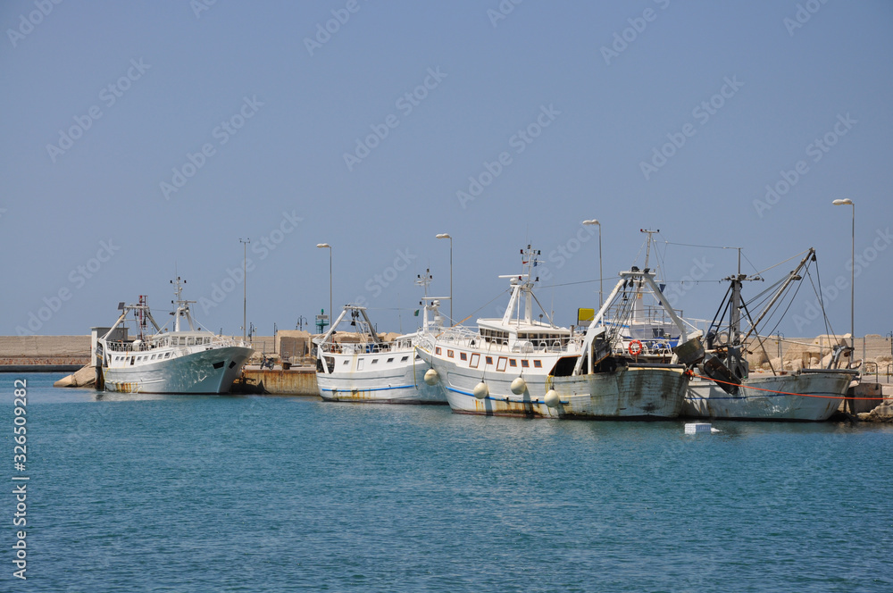 Several old fishing boats alongside in harbour on a sunny summer day.
