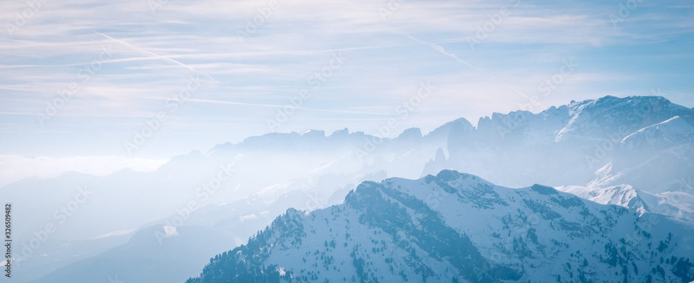 Banner with Morning mountain landscape at a ski resort Campitello di Fassa Italy. Sun and haze in the mountains
