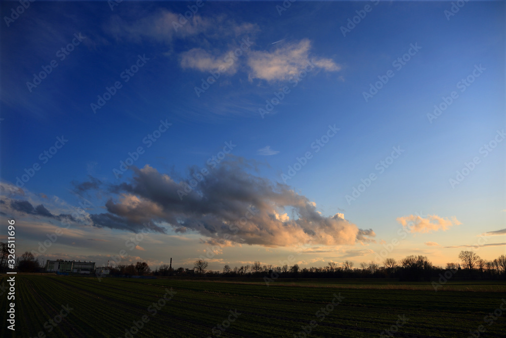 Chmury, obłoki na błękitnym niebie w czasie zachodu słońca.
