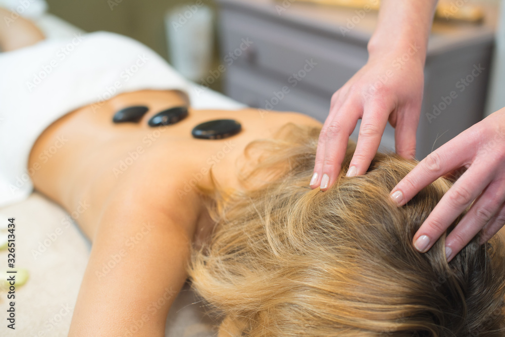 Fototapeta premium spa therapist is placing hot stone on to women back