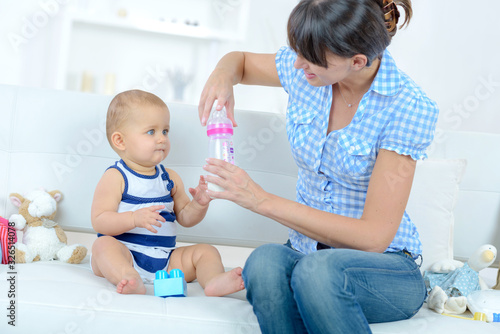 mother feeding baby with milk bottle closeup