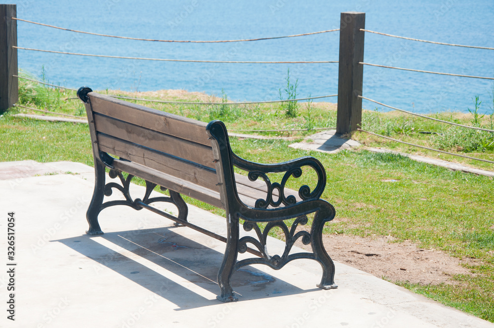 Wooden bench in city park with sea views