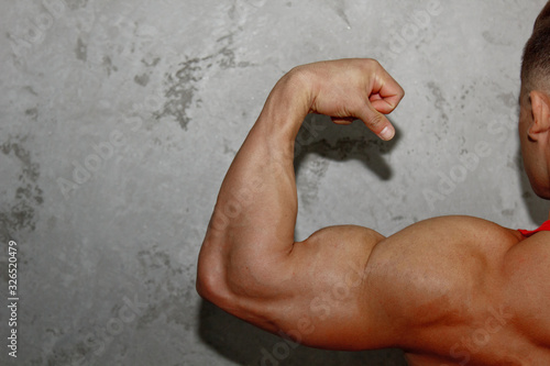 Male powerful biceps closeup. Gym. Body-builder. Beautiful, swollen male body. Trainer, advertising, healthy lifestyle. Bodybuilder. The concept of sports.
