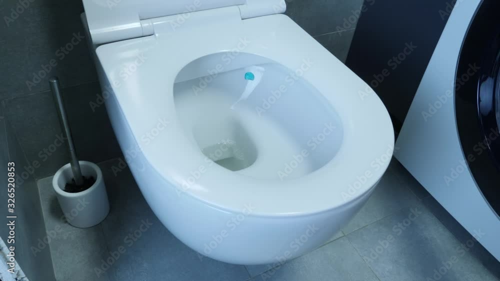 Man hand lifts toilet lid, close up. Male lifting toilet lid in bathroom with grey tiles on